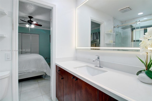 bathroom with ceiling fan, tile patterned floors, toilet, a shower with door, and vanity