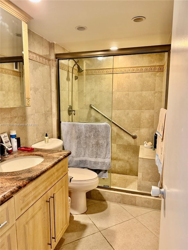 bathroom featuring vanity, tile patterned floors, toilet, tile walls, and walk in shower