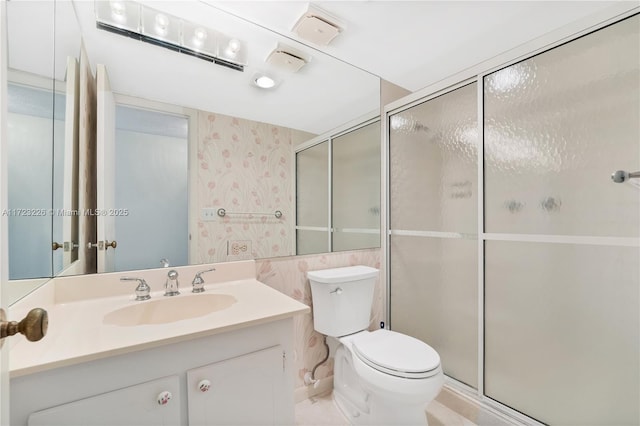 bathroom featuring a shower with door, vanity, and toilet