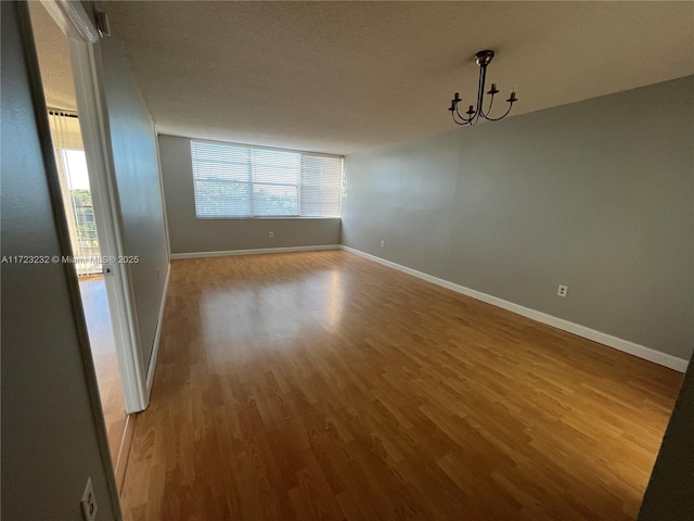 spare room with a chandelier and hardwood / wood-style flooring