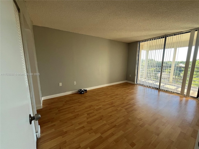 empty room with a textured ceiling, hardwood / wood-style flooring, and floor to ceiling windows