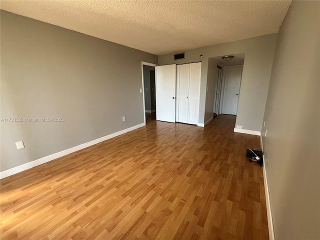 unfurnished bedroom featuring hardwood / wood-style floors, a textured ceiling, and a closet