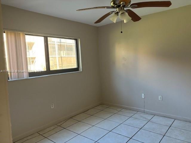 spare room with ceiling fan and light tile patterned floors