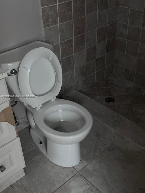 bathroom with a tile shower, vanity, toilet, and tile patterned floors