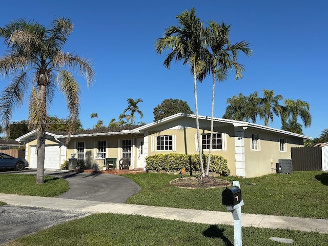 ranch-style house featuring a garage, central air condition unit, and a front yard