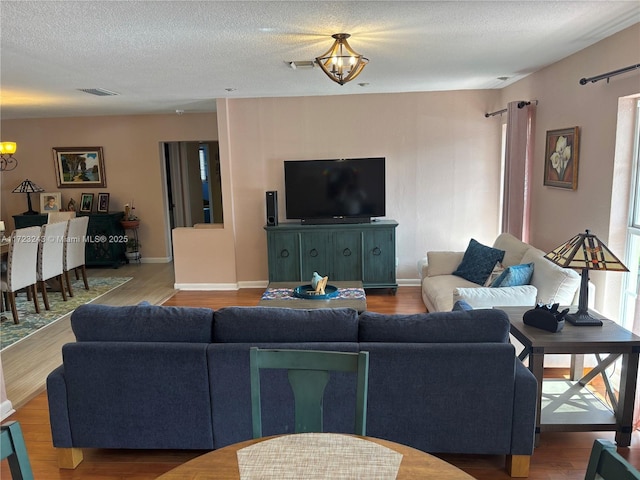 living area featuring a chandelier, a textured ceiling, and visible vents