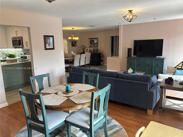 dining room featuring an inviting chandelier, a textured ceiling, and light wood-style floors