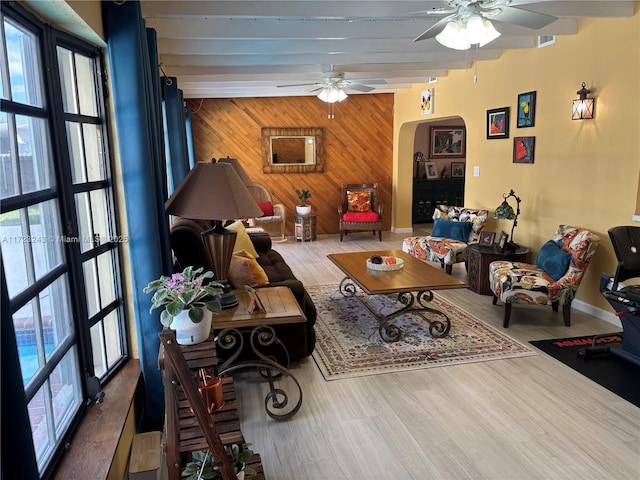 living room with arched walkways, wooden walls, an accent wall, and a healthy amount of sunlight