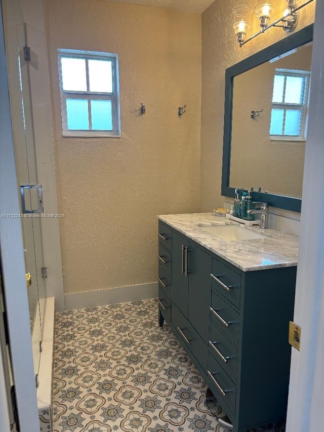 full bath featuring tile patterned flooring, a textured wall, vanity, and baseboards