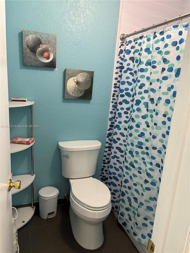 full bath featuring a textured wall, curtained shower, toilet, and tile patterned floors