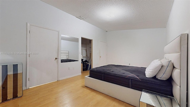 bedroom featuring light wood-type flooring, a textured ceiling, and a closet