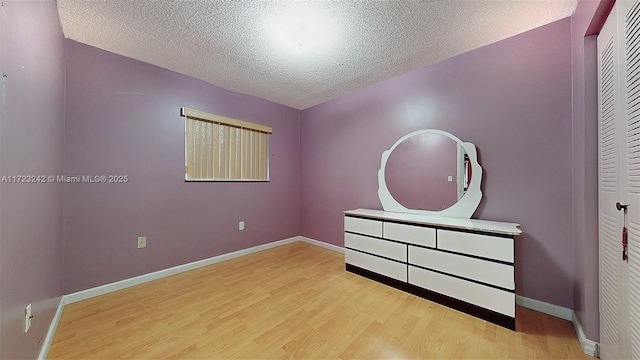 unfurnished bedroom with a textured ceiling, light hardwood / wood-style flooring, and a closet