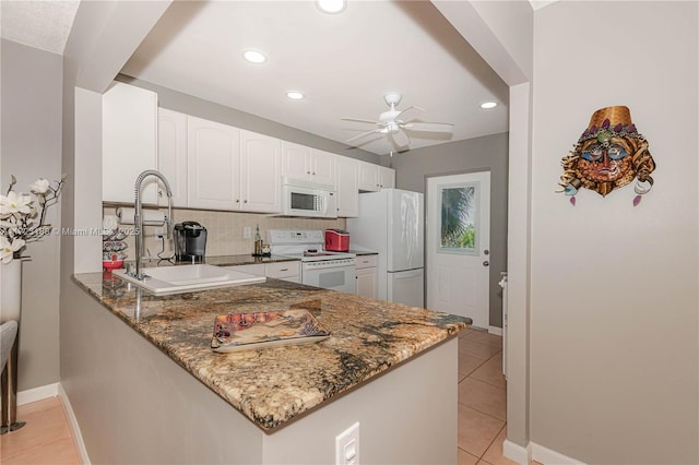 kitchen featuring kitchen peninsula, white appliances, white cabinets, and dark stone counters