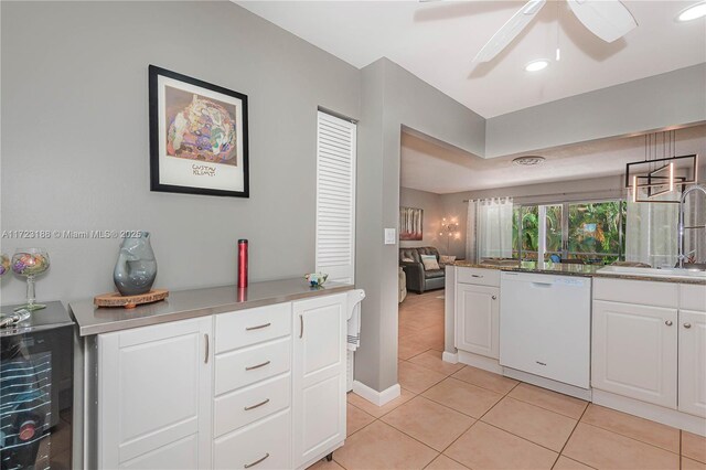 kitchen featuring white dishwasher, sink, light tile patterned floors, white cabinetry, and hanging light fixtures