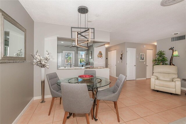 tiled dining area with ceiling fan and a textured ceiling