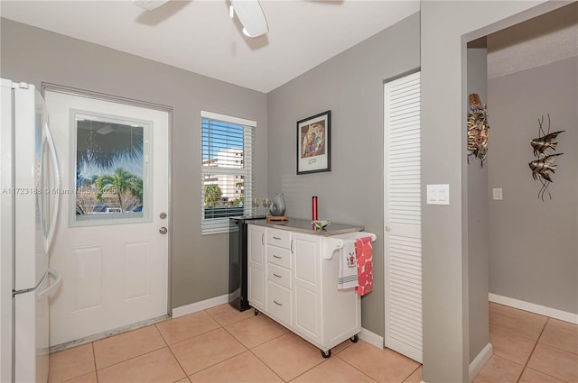 kitchen with white cabinets, ceiling fan, white fridge, and light tile patterned floors