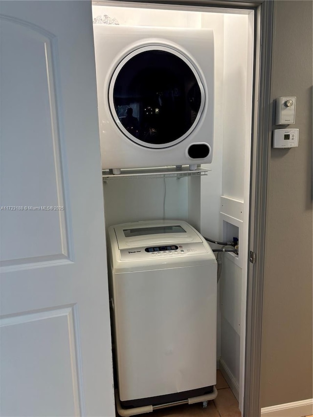 laundry room featuring stacked washing maching and dryer and tile patterned floors