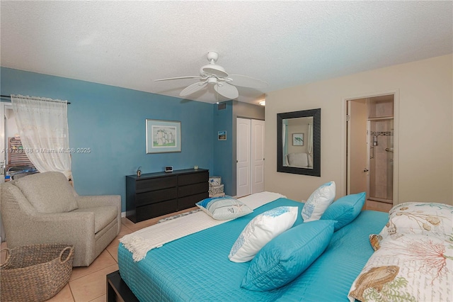 bedroom with ceiling fan, a closet, light tile patterned floors, and a textured ceiling