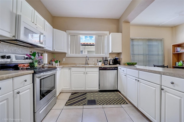 kitchen featuring sink, white cabinetry, stainless steel appliances, and light tile patterned flooring