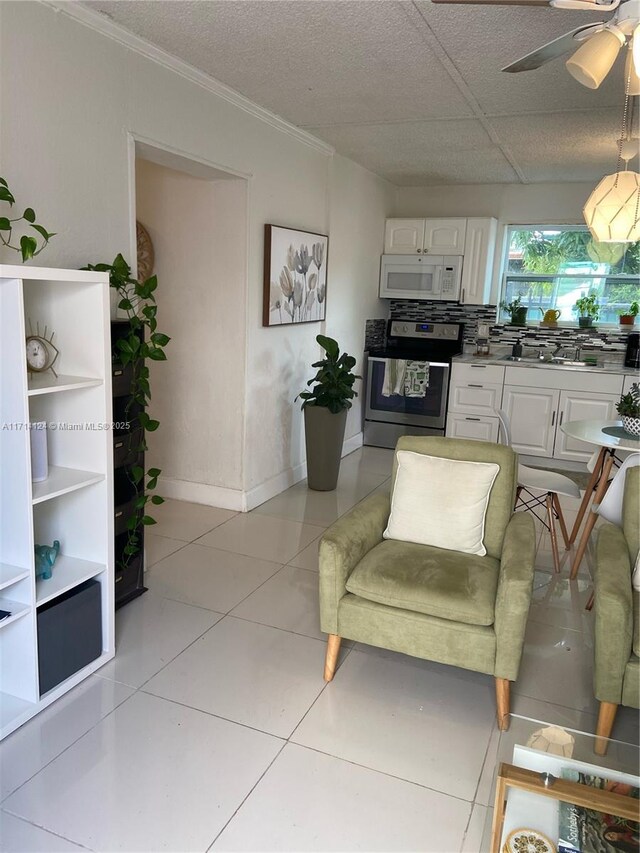 kitchen featuring white cabinets, stainless steel range, decorative backsplash, sink, and light tile patterned floors