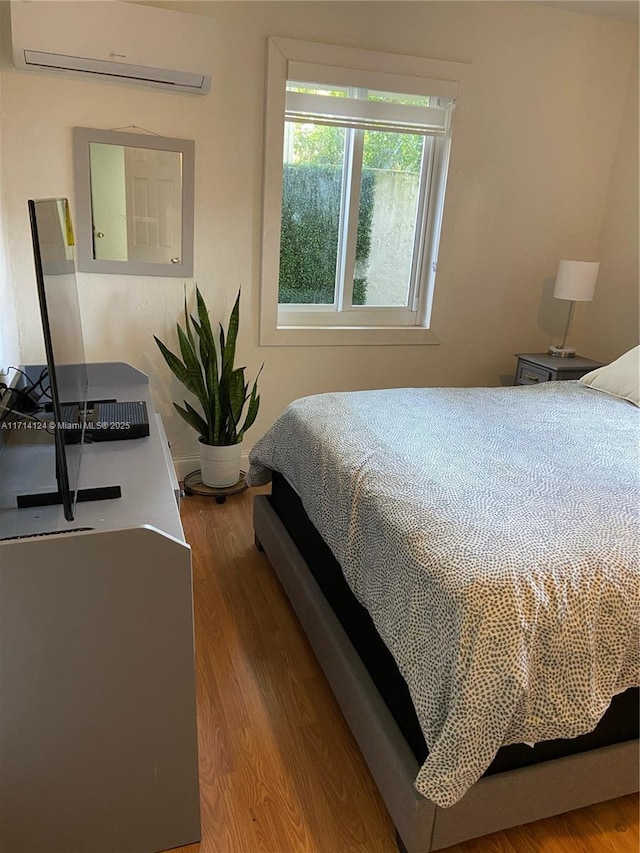 bedroom featuring a wall mounted AC and wood-type flooring