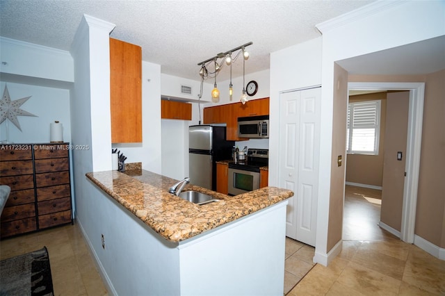 kitchen with light stone counters, appliances with stainless steel finishes, kitchen peninsula, and sink