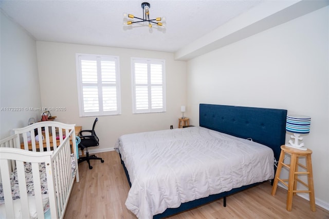 bedroom featuring an inviting chandelier and light hardwood / wood-style floors