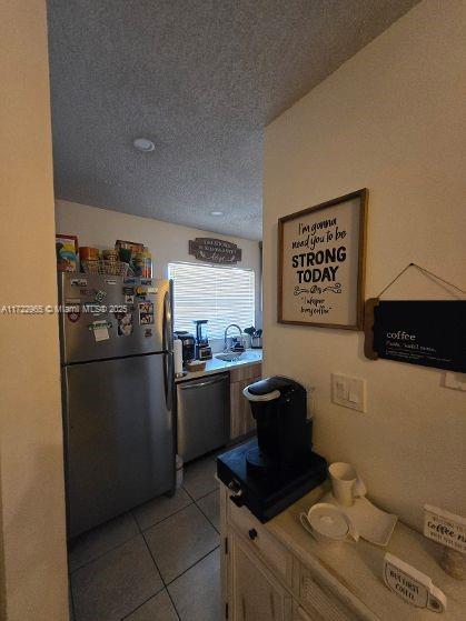 21340 NE 8th Ct Unit 1, Miami, FL 33179 - kitchen with freestanding refrigerator, stainless steel dishwasher, a textured ceiling, light tile patterned floors, and light countertops