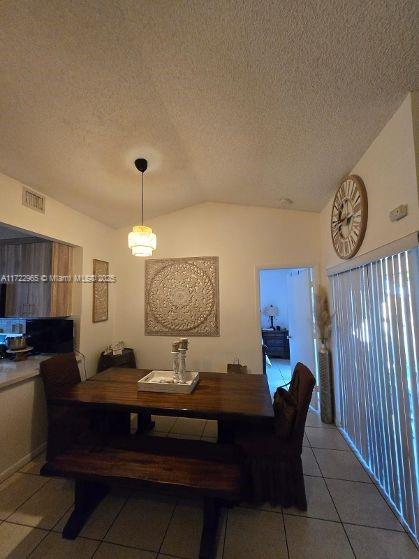 21340 NE 8th Ct Unit 1, Miami, FL 33179 - dining space with light tile patterned floors, lofted ceiling, and a textured ceiling