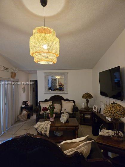 21340 NE 8th Ct Unit 1, Miami, FL 33179 - living room with light tile patterned floors, vaulted ceiling, and a chandelier