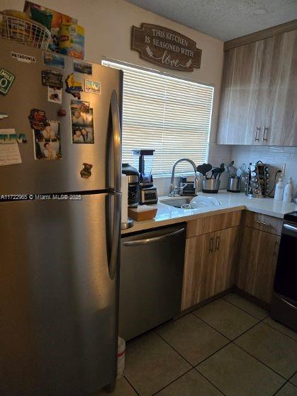 21340 NE 8th Ct Unit 1, Miami, FL 33179 - kitchen with appliances with stainless steel finishes, a sink, light countertops, light tile patterned floors, and a textured ceiling