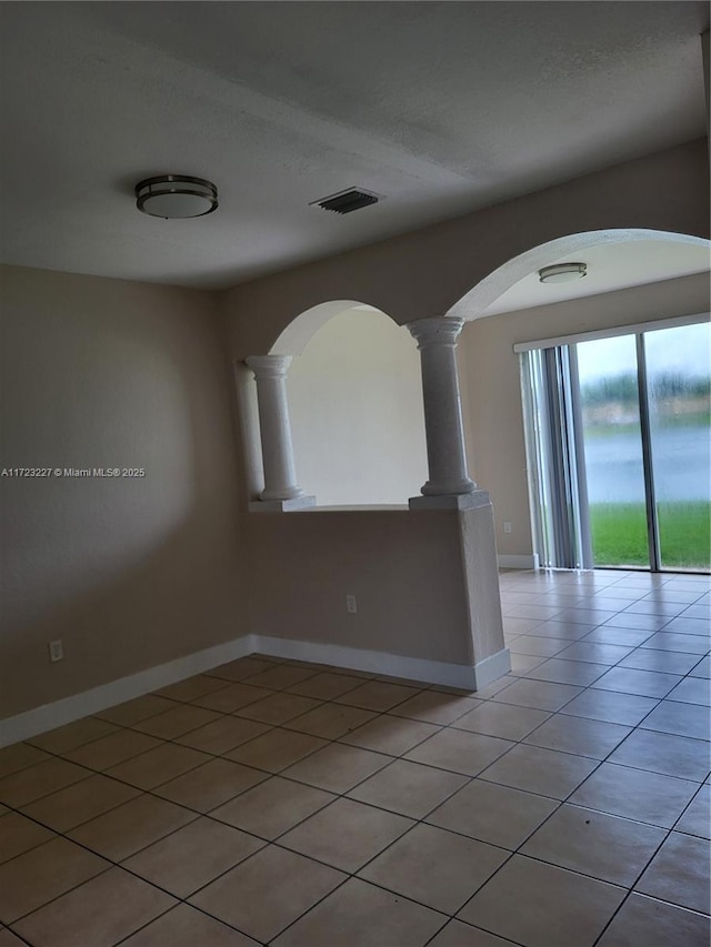 tiled empty room featuring decorative columns