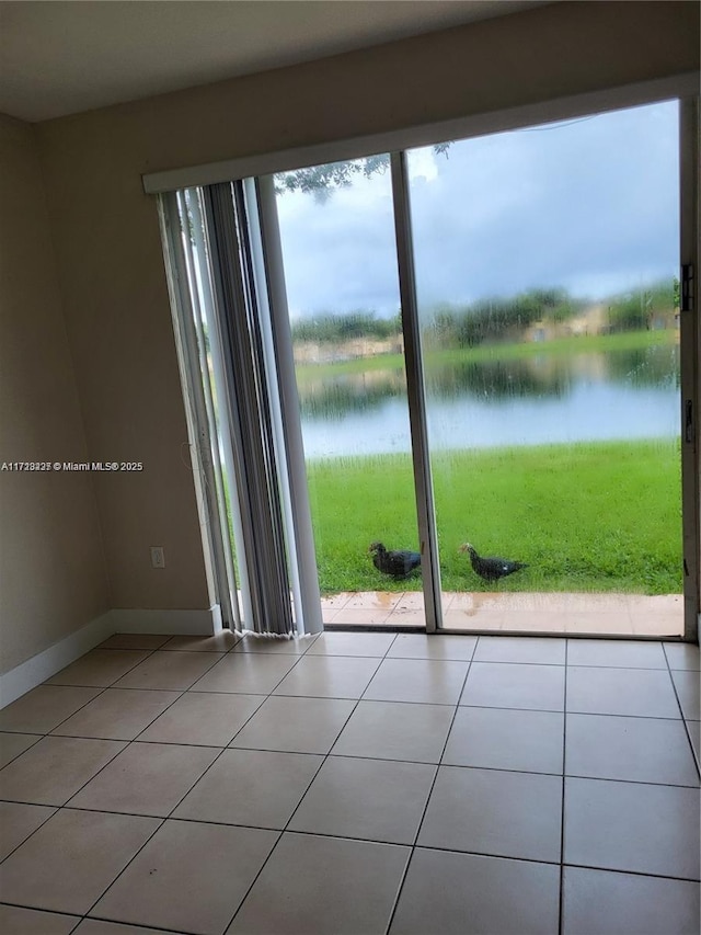 spare room with a water view and light tile patterned floors