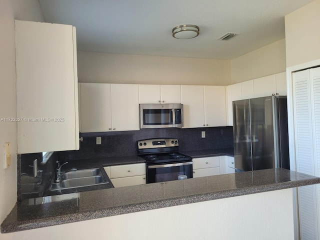 kitchen featuring kitchen peninsula, decorative backsplash, stainless steel appliances, sink, and white cabinetry