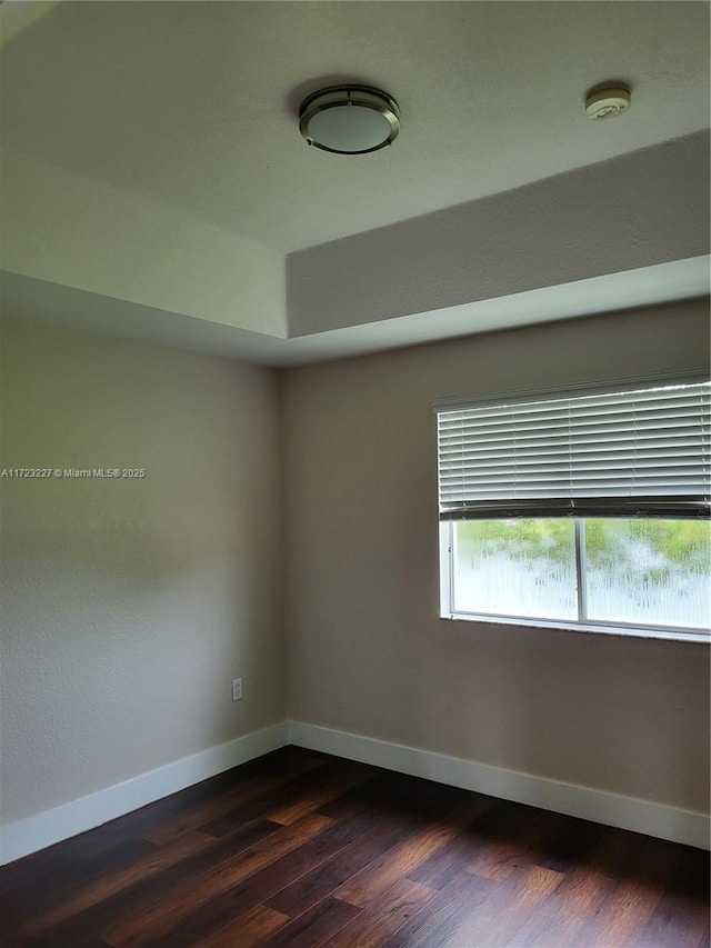 unfurnished room with dark wood-type flooring