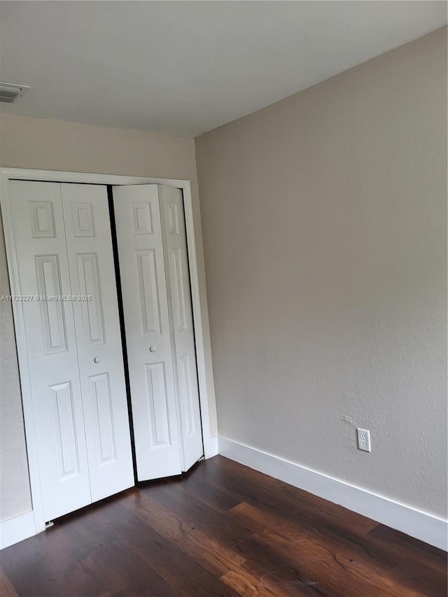 unfurnished bedroom with a closet and dark hardwood / wood-style flooring