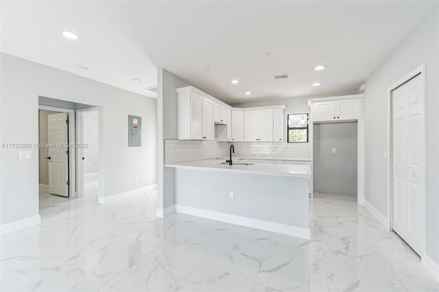 kitchen with kitchen peninsula, sink, white cabinets, and electric panel