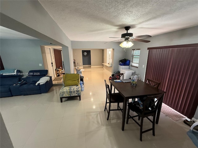 tiled dining area with a textured ceiling, ceiling fan, and vaulted ceiling