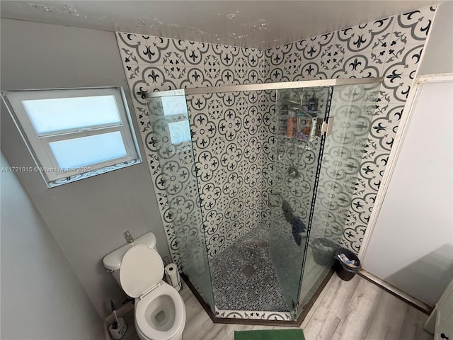 bathroom featuring hardwood / wood-style flooring, toilet, and a shower with shower door