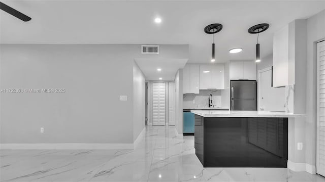 kitchen with white cabinetry, kitchen peninsula, pendant lighting, decorative backsplash, and appliances with stainless steel finishes