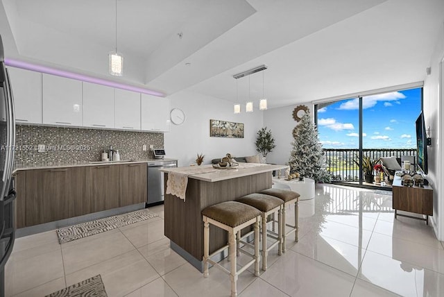 kitchen featuring white cabinetry, dishwasher, a wall of windows, pendant lighting, and a kitchen island