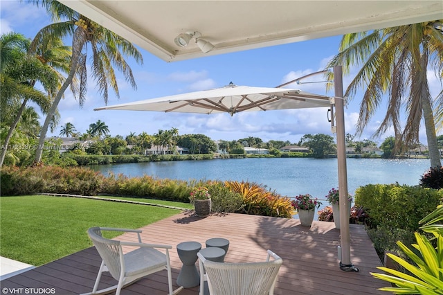 wooden terrace with a water view and a yard