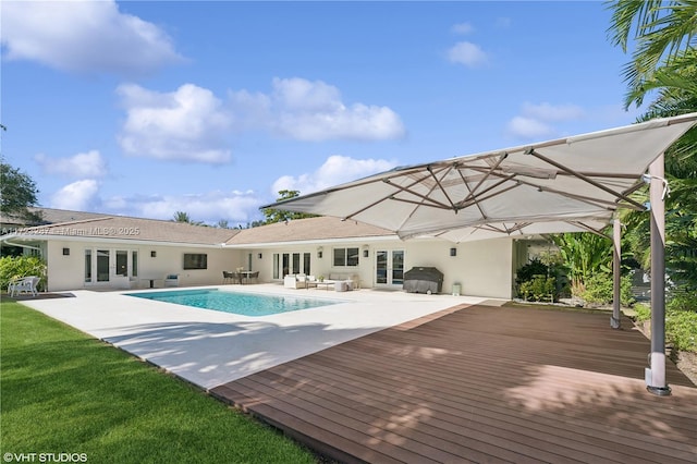 view of pool with grilling area, french doors, and a deck