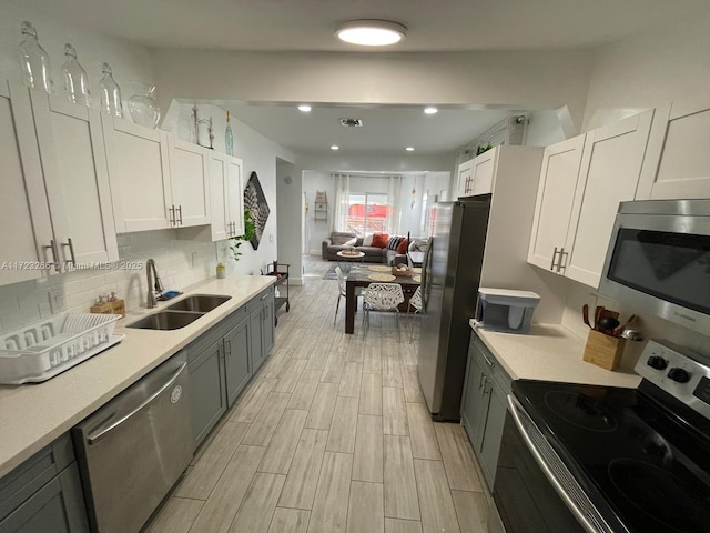 kitchen with tasteful backsplash, gray cabinets, sink, stainless steel appliances, and white cabinets