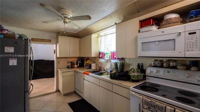 kitchen featuring white appliances, sink, ceiling fan, light tile patterned floors, and white cabinetry