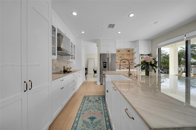 kitchen featuring tasteful backsplash, exhaust hood, white cabinetry, and light hardwood / wood-style flooring