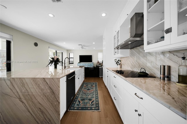 kitchen featuring black appliances, wall chimney range hood, white cabinetry, ceiling fan, and light stone counters