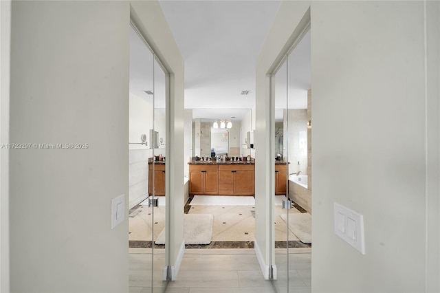 hallway with sink and a chandelier