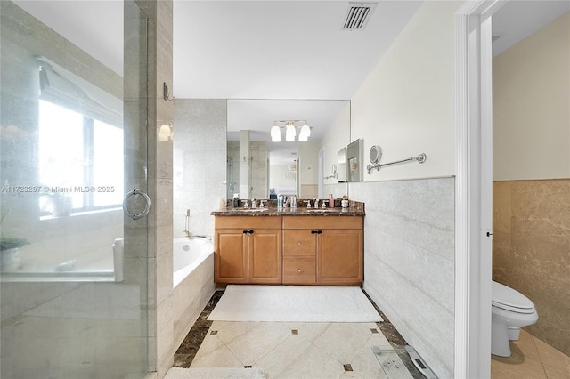 full bathroom with toilet, tile patterned flooring, tile walls, shower with separate bathtub, and vanity