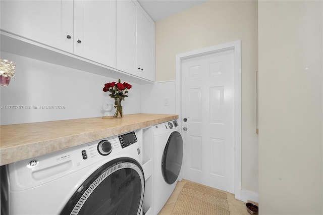 clothes washing area featuring washing machine and dryer and cabinets